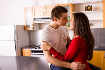 Young couple hugging and talking in the kitchen.
