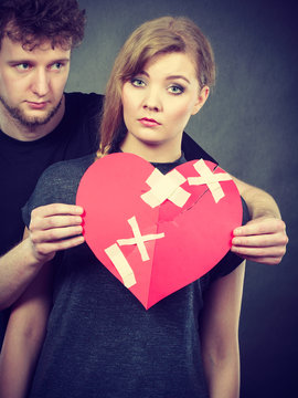 Sad couple holds broken heart.