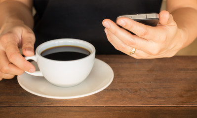 Hand on coffee cup and smartphone