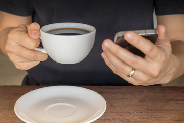 Hand on coffee cup and smartphone