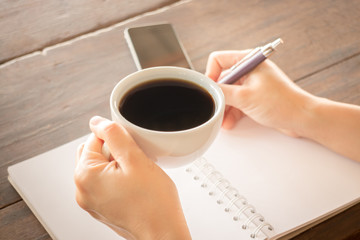 Hand on coffee cup and writing