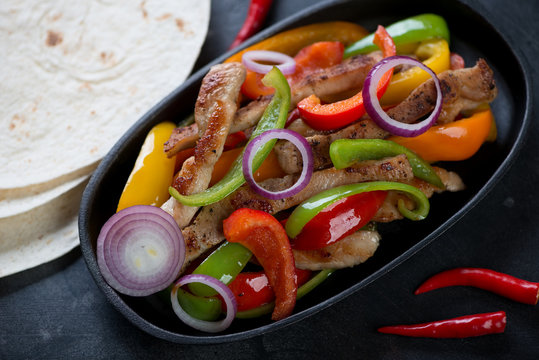 Fajitas with colorful bell peppers and pork meat in a frying pan