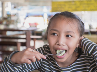 Cute Asian child eatting in a restaurant.