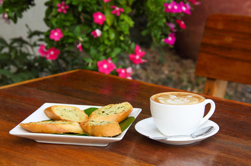 Cup of latte coffee and homemade garlic herb bread on table