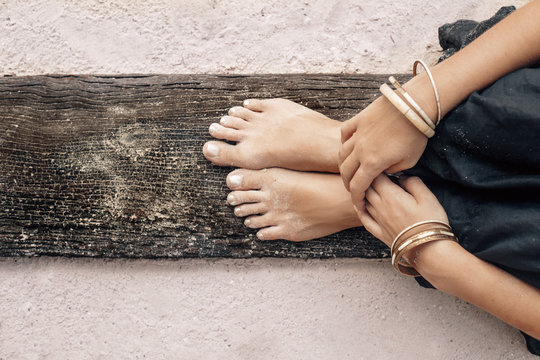 woman hands and legs close up on a piece of wood outdoors