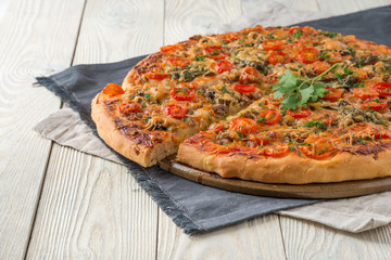 cooked pizza on a wooden background with cut slice