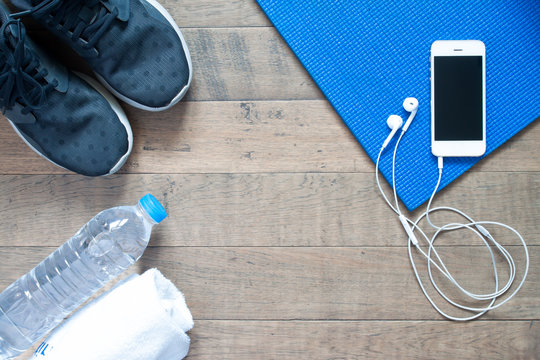 Overhead view of smartphone with earphone on blue yoga mat with