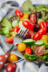 Tomato on a fork close up. Healthy salad of red and yellow cherry tomato and herbs.