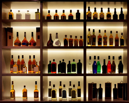 Various alcohol bottles in a bar, back light, logos removed