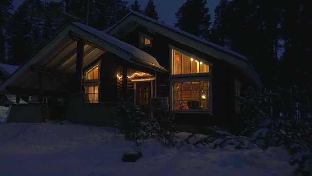 Moving by cozy wooden house in snowy forest village at winter night .