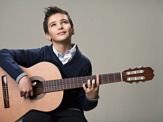 Boy playing with pleasure on acoustic guitar.
