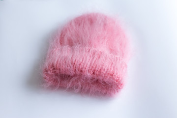Much fluffy and warm hat pink knitted by hand on a white background