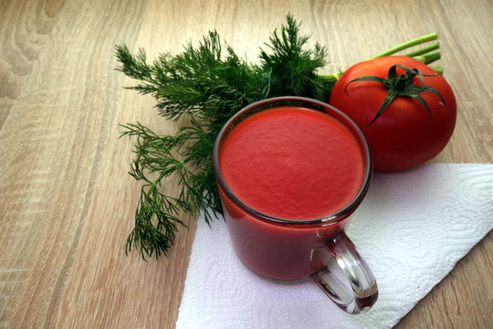 Glass full of tomato juice with vegetables on rustic background 