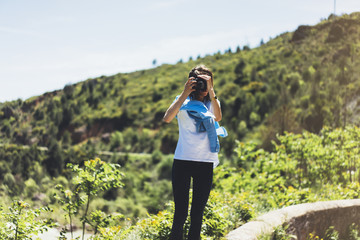Tourist traveler photographer taking pictures of amazing landscape on vintage photo camera on background valley view mockup sun flare, hipster girl enjoying peak mountain, nature holiday concept