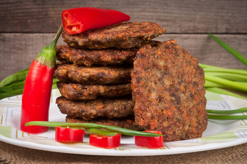 liver pancakes or cutlets with chili pepper and green onions on a wooden background
