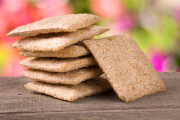stack of crisp bread on a wooden table with blurred garden background