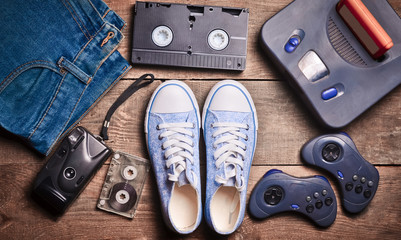 Back in the 90s. Shoes, audio tapes, video tapes, game console, jeans. Top view. Flat lat. 