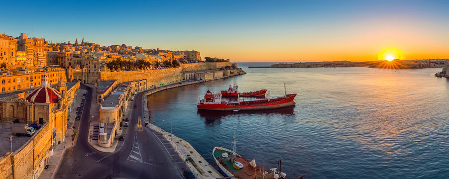 Valletta, Malta - Panoramic skyline view of Valletta and the Grand Harbor with beautiful sunrise, ships and clear blue sky