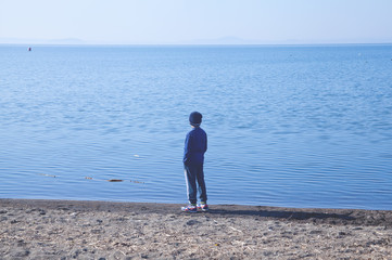 Young boy watching lake panorama