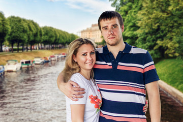 Obraz premium Young man and woman, woman standing and hugging in the city on the background of the urban landscape