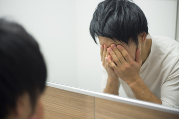 洗面所で顔を洗う男性