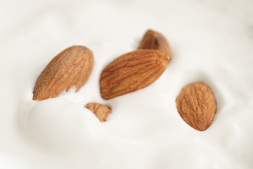 macro shot of homemade yogurt with almonds in wood bowl on wooden table, shallow focus