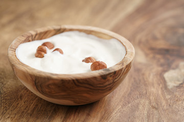 Fototapeta na wymiar homemade yogurt with hazelnuts in wood bowl on wooden table, shallow focus