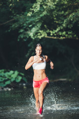 Fototapeta premium Attractive young woman running through river water. Hard training and sport theme.