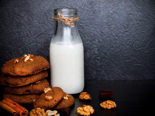 A glass of milk and healthy cookies on dark background