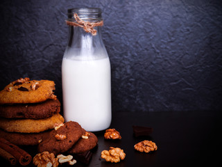 A glass of milk and healthy cookies on dark background