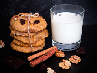 A glass of milk and healthy cookies on dark background