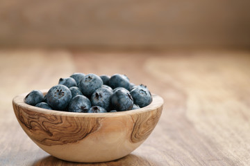 fresh blueberries in wood bowl on table with copy space, shallow focus