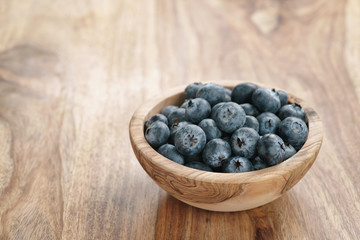 fresh blueberries in wood bowl on table with copy space, shallow focus