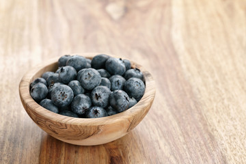 fresh blueberries in wood bowl on table with copy space, shallow focus