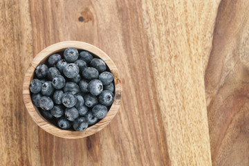 fresh blueberries in wood bowl on table with copy space, shallow focus
