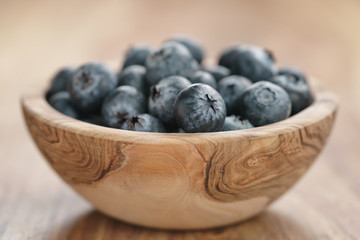 closeup fresh blueberries in wood bowl on table, shallow focus