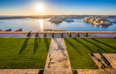Valletta, Malta - Beautiful sunrise at the famous saluting battery of Valletta with Grand Harbor and Senglea and Brigu at background. Blue sky and sunlight.