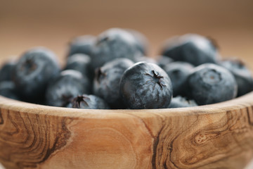 closeup fresh blueberries in wood bowl on table, shallow focus