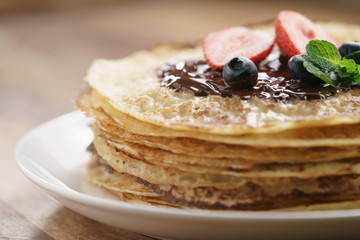 fresh blinis or crepes with melted dark chocolate and berries, closeup photo