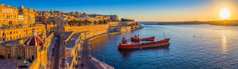Valletta, Malta - Panoramic skyline view of Valletta and the Grand Harbor with beautiful sunrise, ships and clear blue sky - obrazy, fototapety, plakaty