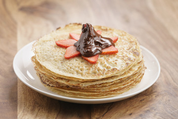 premium dark chocolate poured on blinis with strawberry, shallow focus