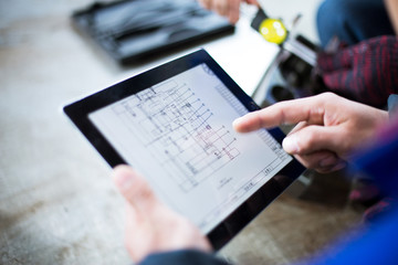 technician holds tablet with mechanical drawing - obrazy, fototapety, plakaty