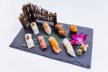 Premium Sushi Set Include Engawa, Hamachi, Hotate, Toro, Foie Gras, Salmon, Sea Urchin and Tai Served with Wasabi and Prickled Ginger on The Black Stone Plate.