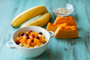 Porridge for breakfast of millet with pumpkin and bananas. Cooking. On a wooden background