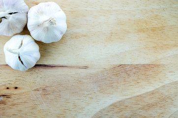 Wooden Chopping Board with Three Garlics on White Background.