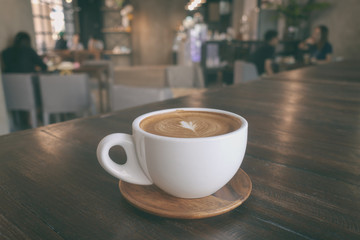 A cup of coffee latte on wooden table in warm cafeteria