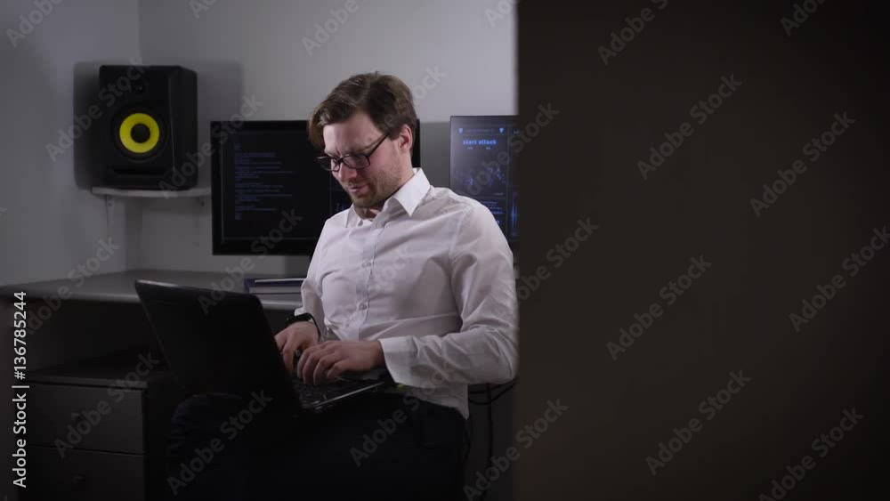 Poster portrait of a young man working on laptop and setting his gadget with smartwatch on his hand. develo