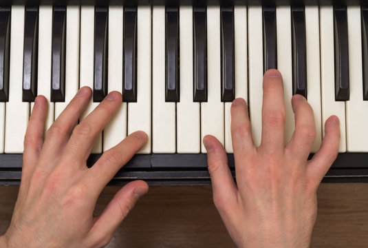 Man's hands playing music on the synthesizer