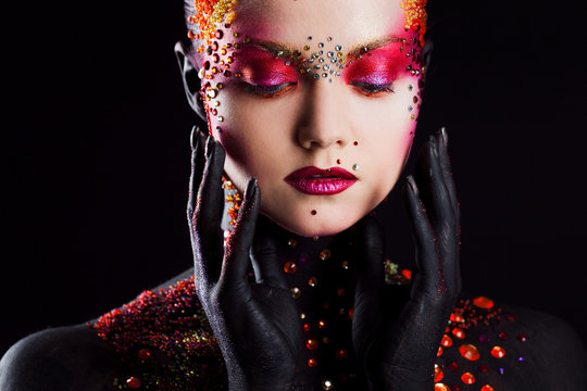 Young attractive girl in bright art-makeup, body painting. Touching face
