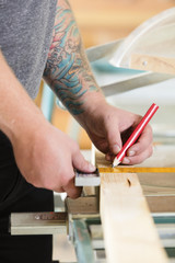 Carpenter measures length of a wood plank before sawing